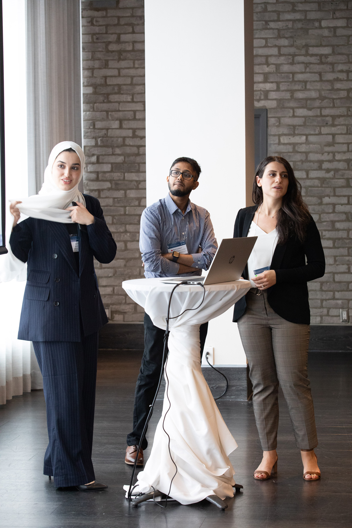 Three people standing around table with laptop