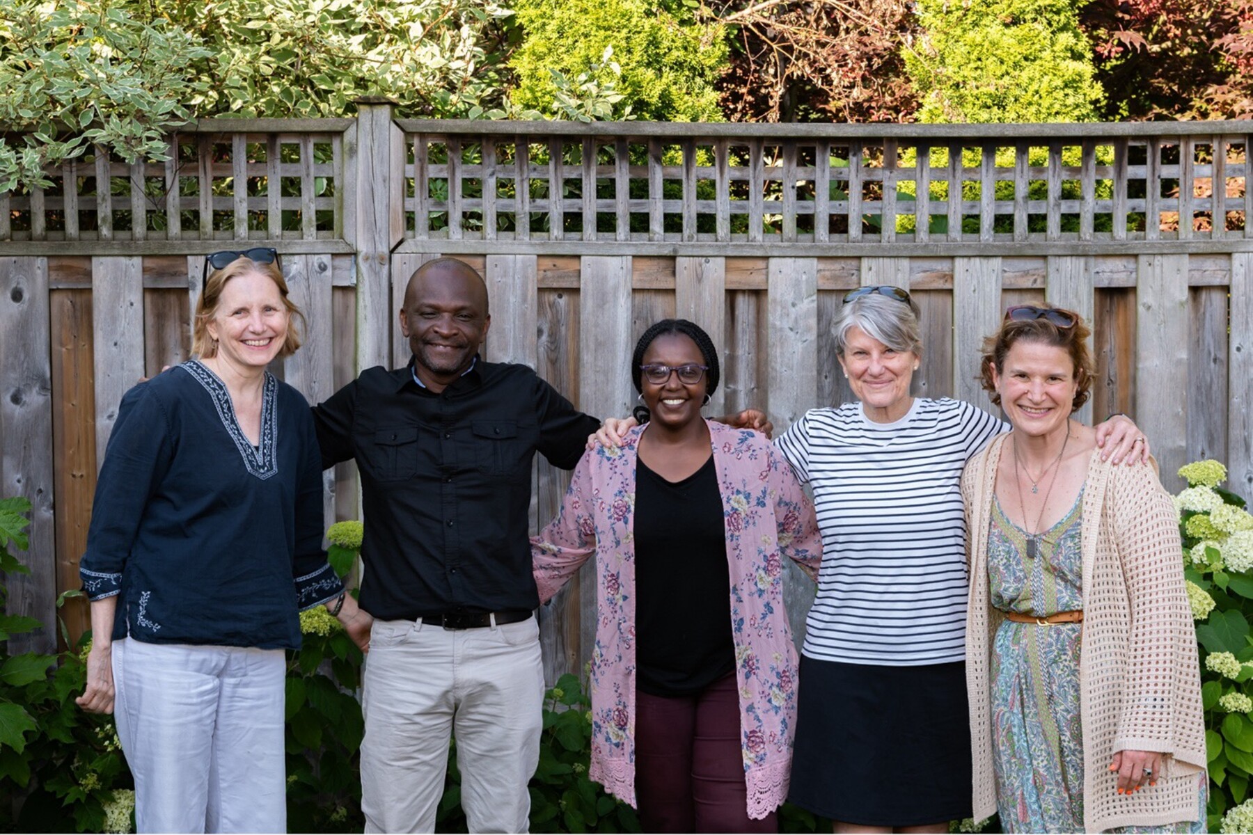 People arm in arm in backyard, posing for camera