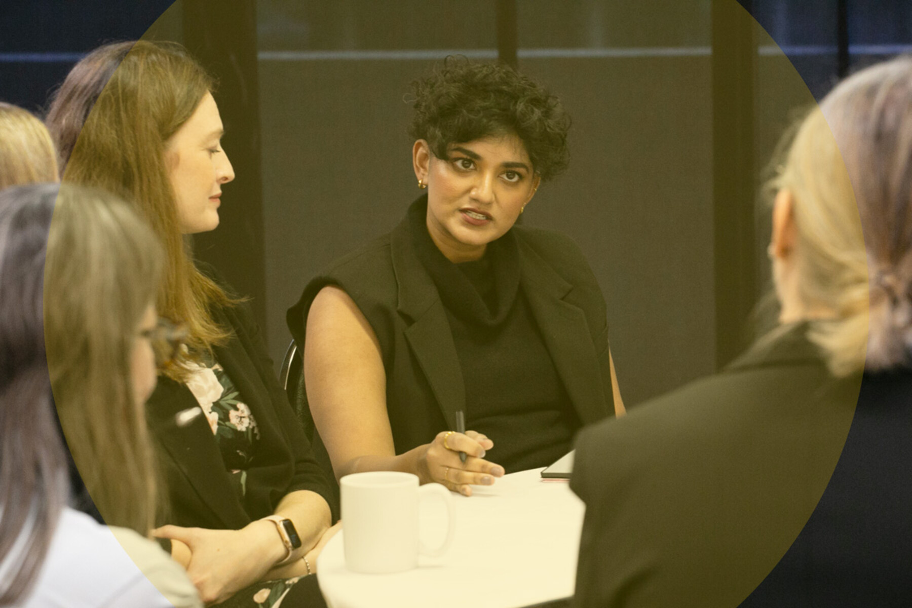 Woman talking to others seated at a table