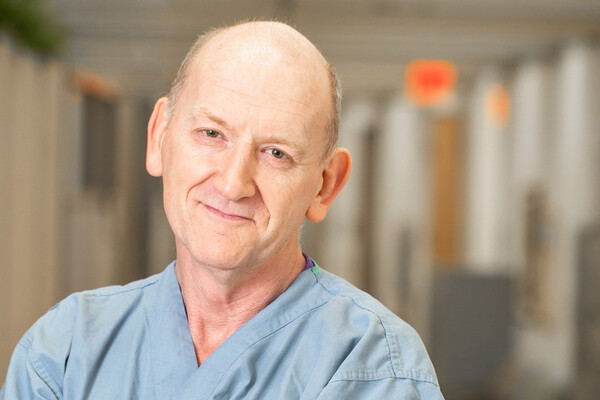 Picture of Greg Ryan in scrubs in hospital corridor