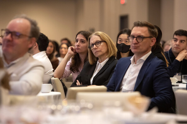 Professor seated at table with others, listening to a presentation