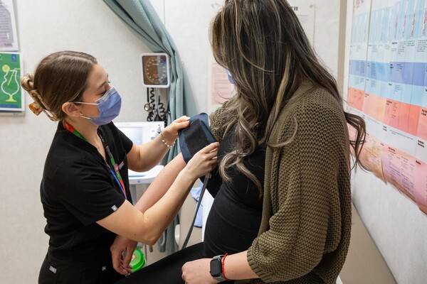 A visibly pregnant woman receiving care from a health-care professional