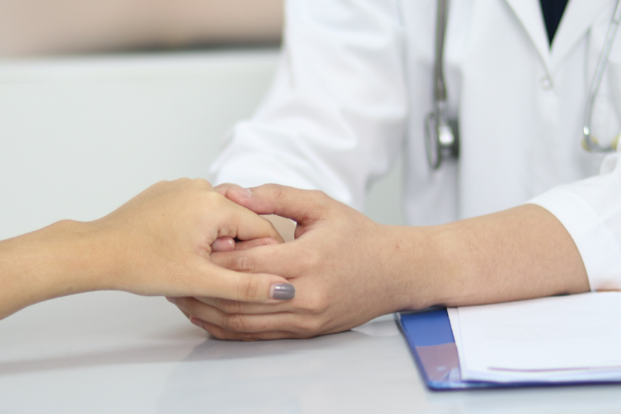 Doctor holds hands with patient