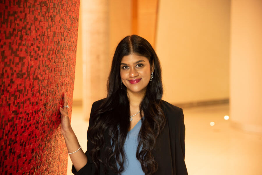 Aditi Sivakumar, leaning against red wall 