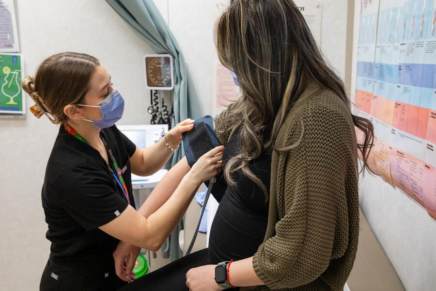 A visibly pregnant woman receiving care from a health-care professional