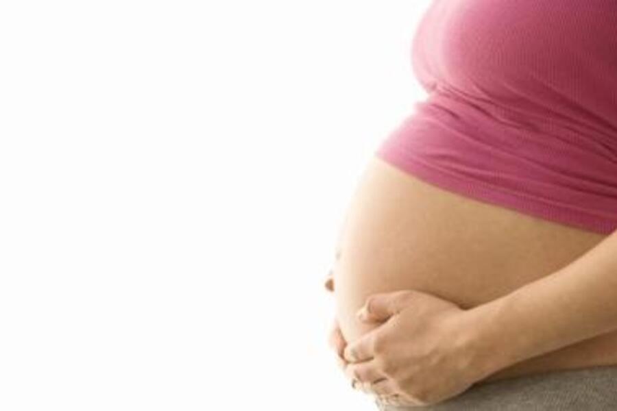 Visibly pregnant woman holding her belly