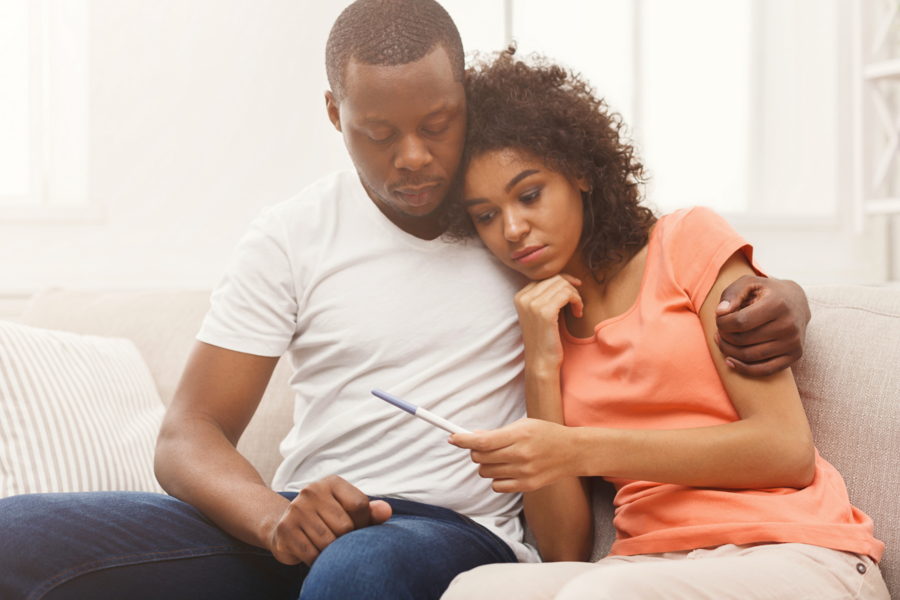 Couple hugging while holding pregnancy test