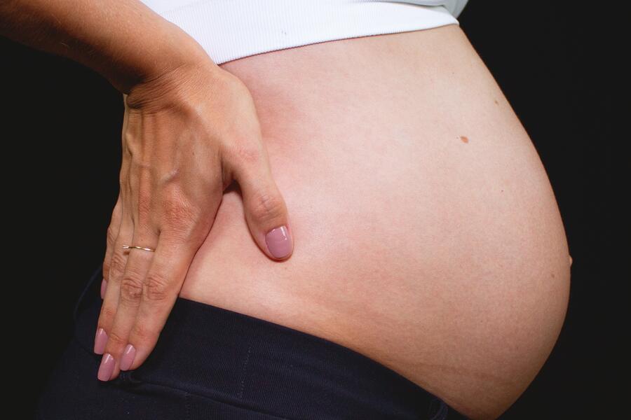 Pregnant woman from the side with hands on back