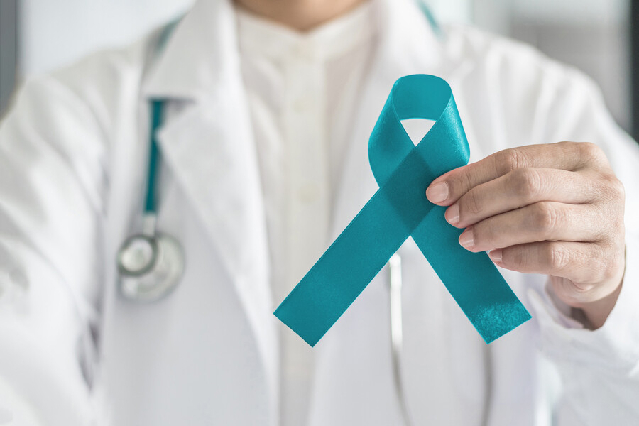 A doctor holding a teal ribbon in honour of Ovarian Cancer Awareness Month