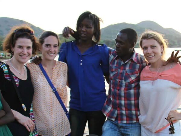 People arm in against backdrop of mountains