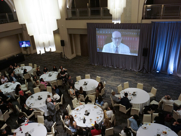 Romero on large video screen in front of seated attendess