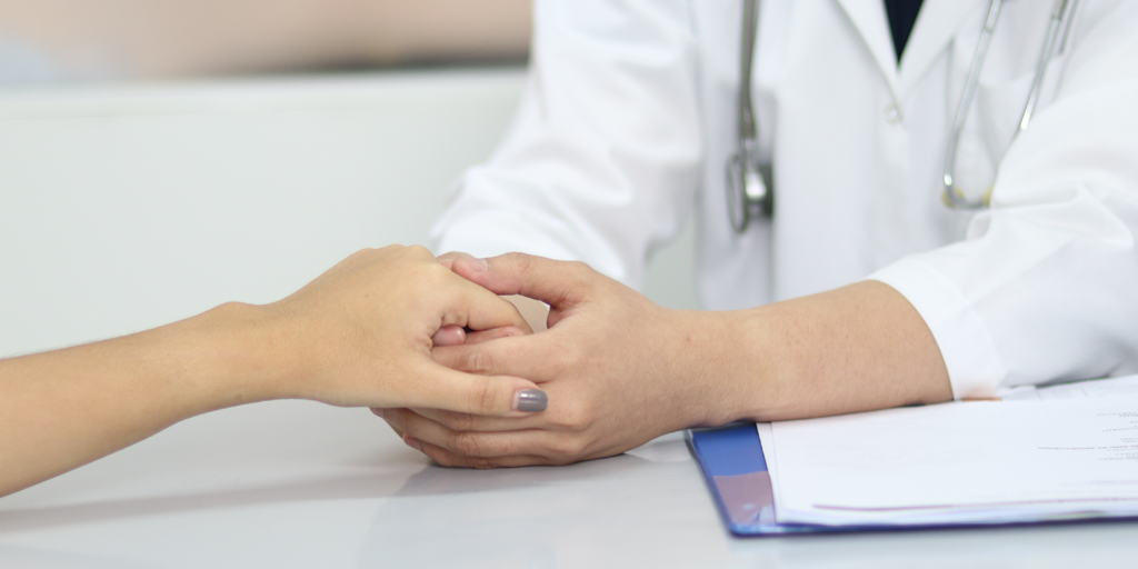 Doctor holds hands with patient