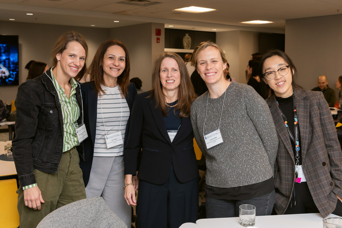 Five women shoulder to shoulder in conference room