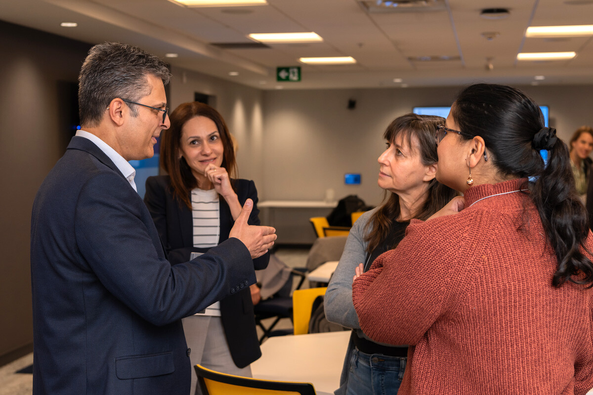 Man in suit gesturing while talking to three participants