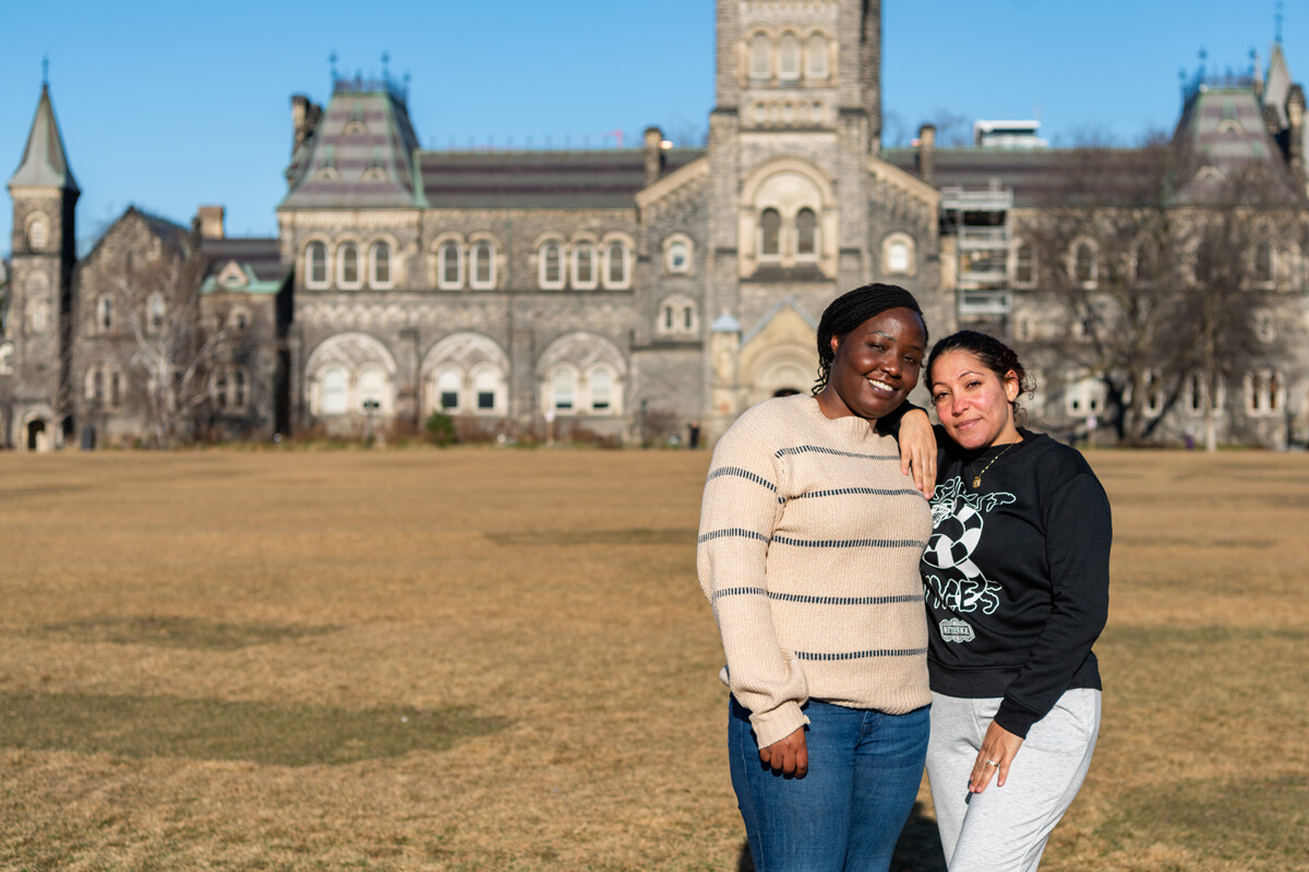 Two women together with university building in the distance