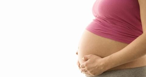 Visibly pregnant woman holding her belly